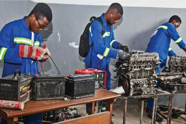 Apprenants du CFIS Mbour testant des batteries et démontant un moteur dans l'atelier de mécanique automobile